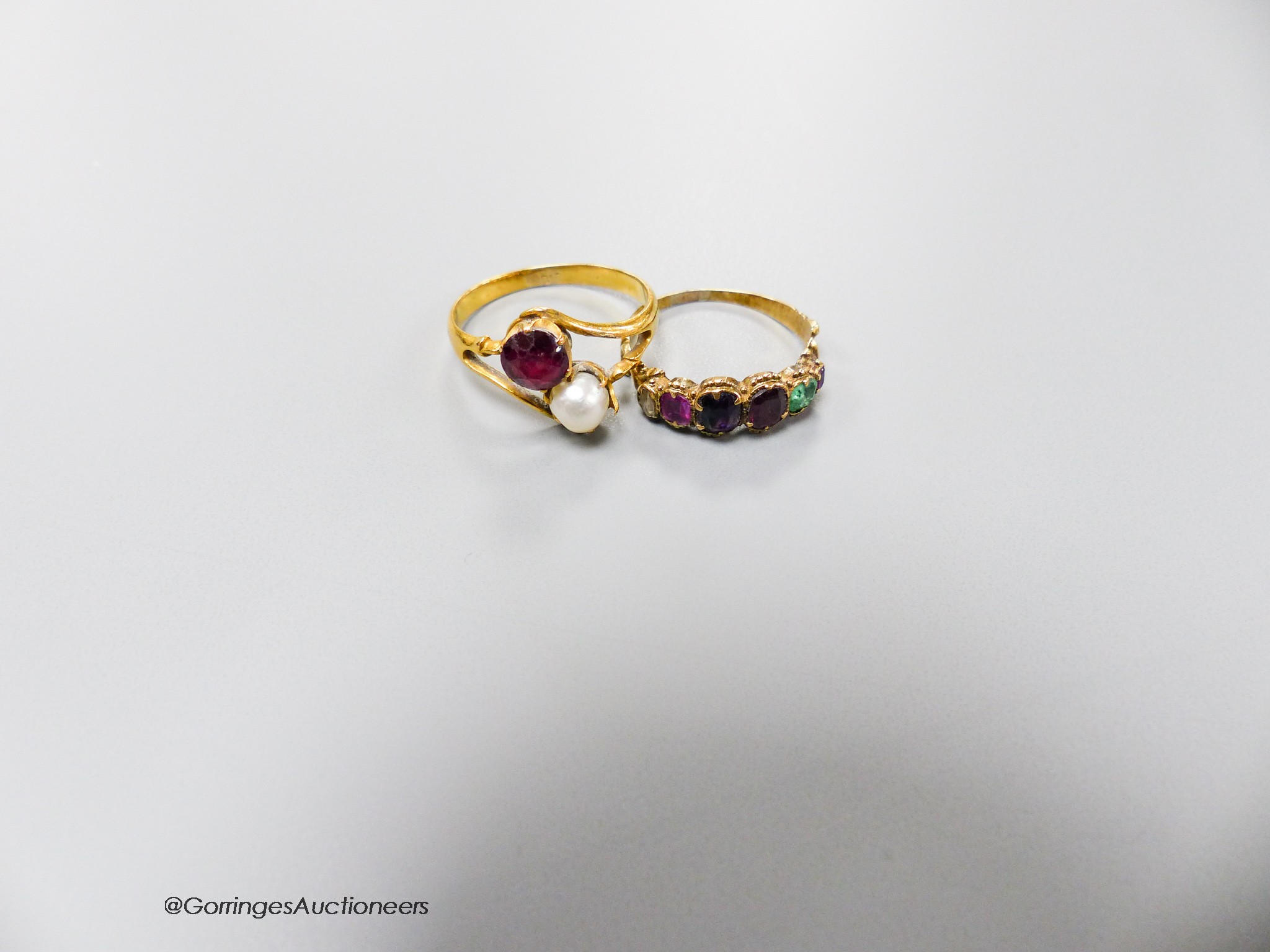 A Victorian yellow metal and graduated multi gem set 'Regard' half hoop ring, size L and a yellow metal ruby and cultured pearl set crossover ring, size O, gross weight 4.7 grams.